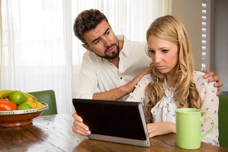 Man consoling his wife after reading bad news